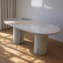 oval dining table in cream marble with natural veining and fluted support