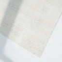 Beige rug on a white floor with soft shadows