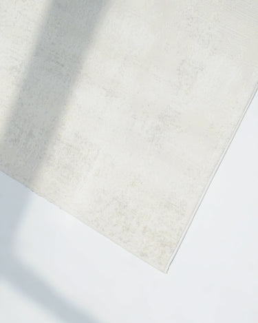 Beige rug on a white floor with soft shadows