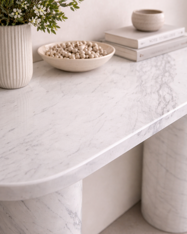 Detail of Evelyn console table surface in White Volakas marble showing soft grey veining and refined curved edge finish
