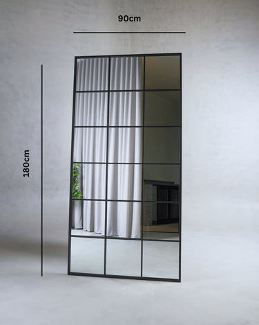 Vian full length standing mirror with black metal grid frame leaning against wall