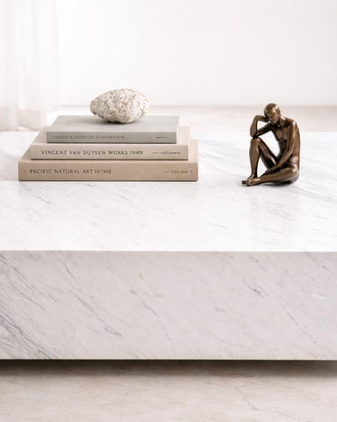 Althea White Volakas marble coffee table styled with books and decor, showcasing polished surface and natural stone veining
