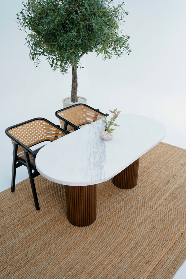 Modern dining table with marble top and wicker chairs in a minimalistic setting.